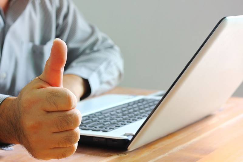 Thumb up near laptop computer